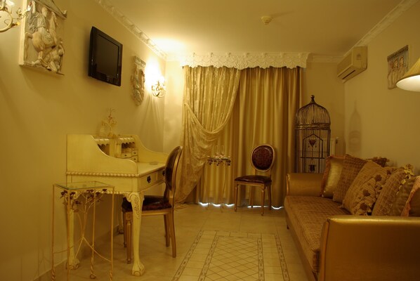 A living room with a sofa, a chair, a table, and a television. - Parthenon Art Hotel (Katerini)