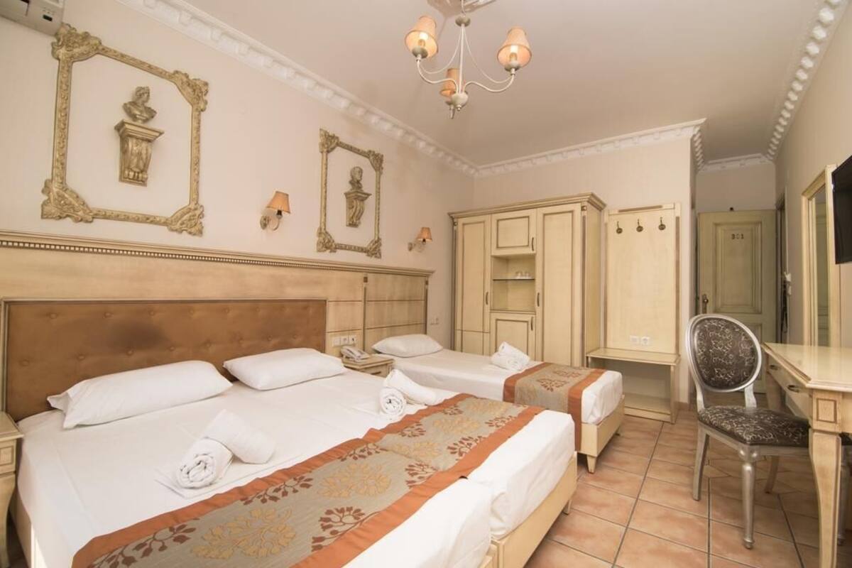 Quarto de hotel com duas camas, uma escrivaninha e uma cadeira.
