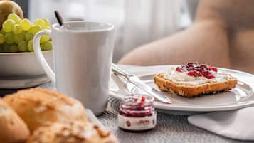 En frukostuppsättning med en tallrik rostat bröd, en skål med vindruvor, en mugg och en liten burk marmelad.