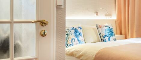 A hotel room with a bed, a window, and a door.