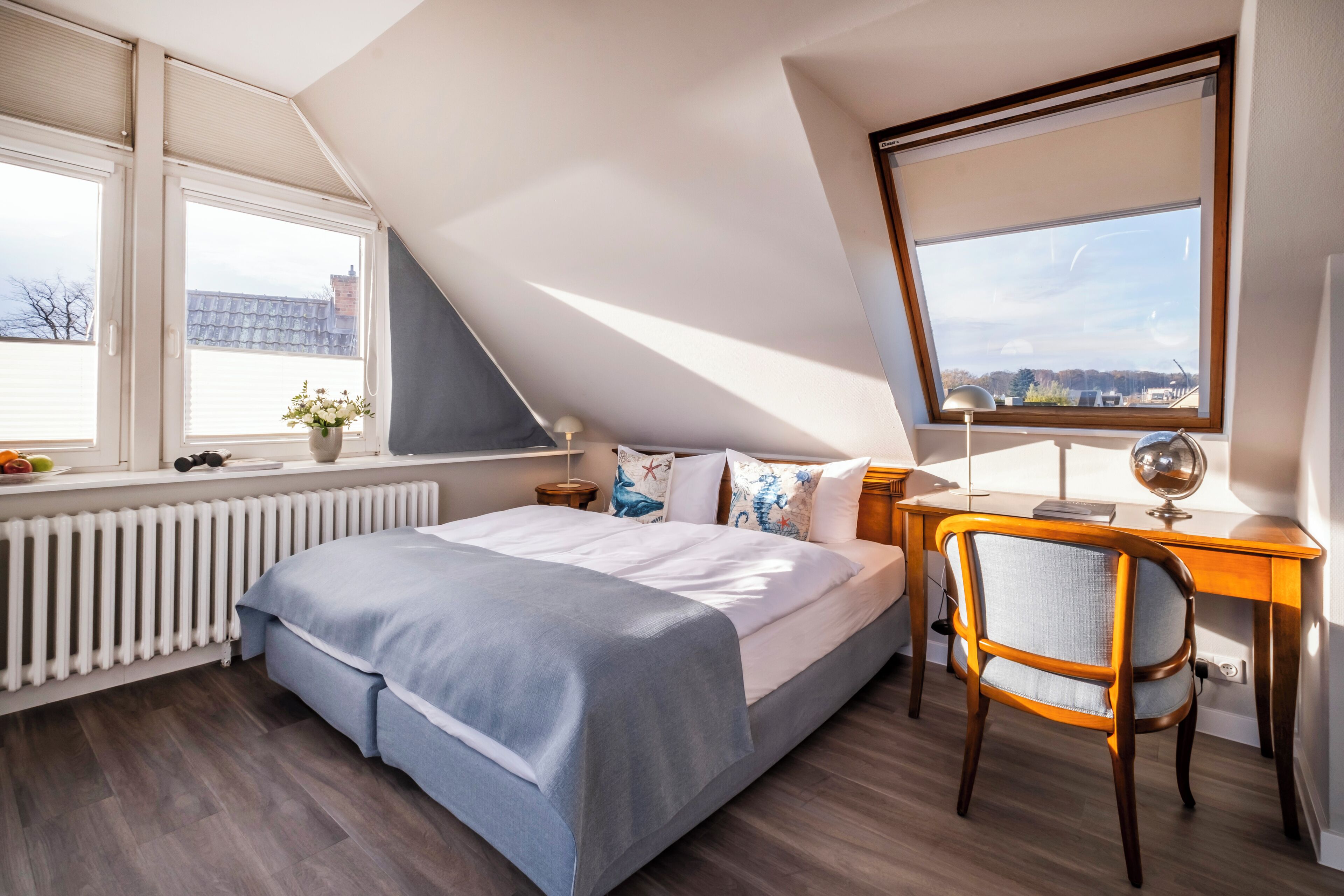 Un dormitorio con cama, escritorio, silla y ventana con vistas.