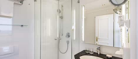 A modern bathroom with a glass-enclosed shower, a black countertop sink, and a large mirror.