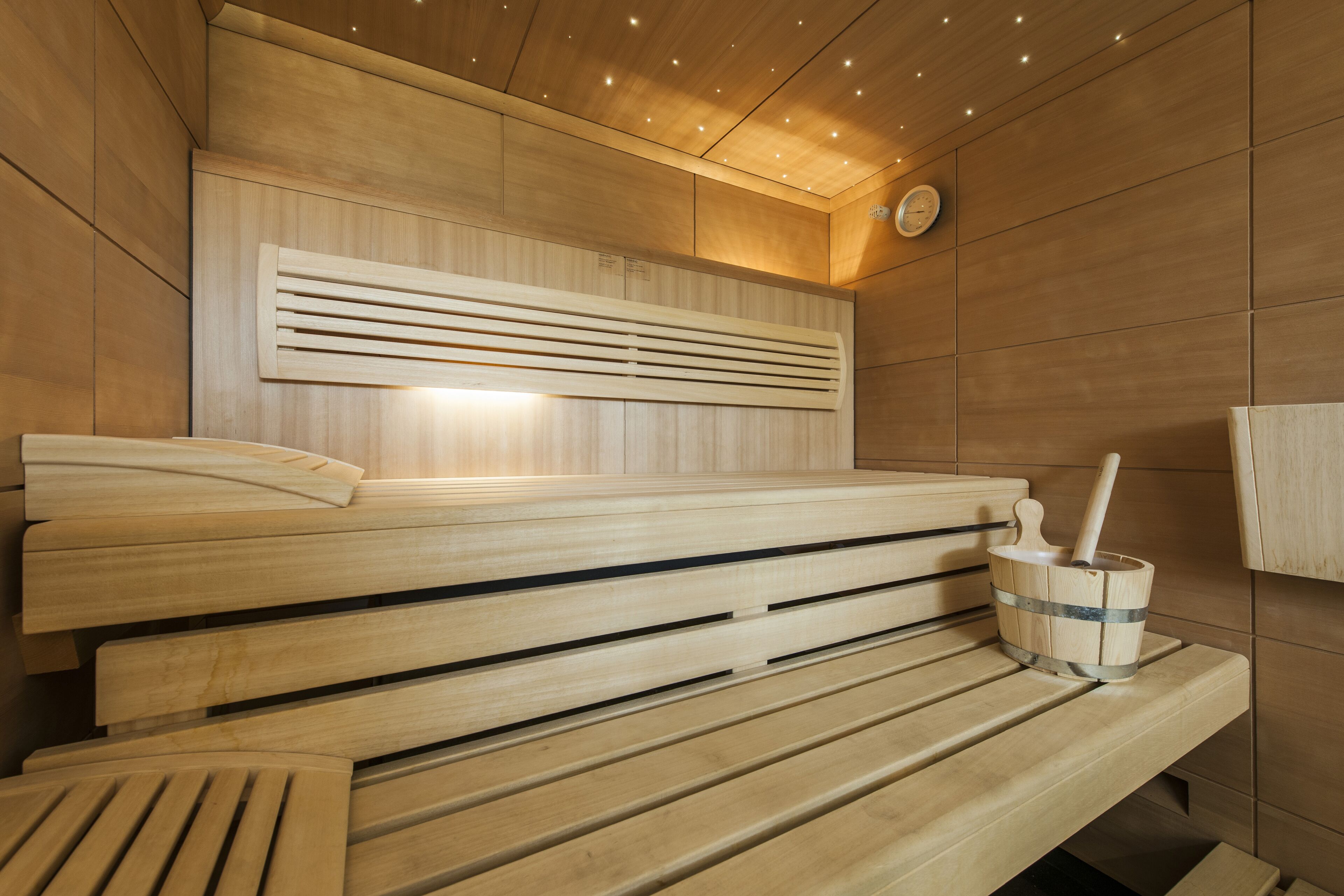 A sauna with wooden benches and a wooden bucket with a brush.