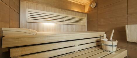 A sauna with wooden benches and a wooden bucket with a brush.
