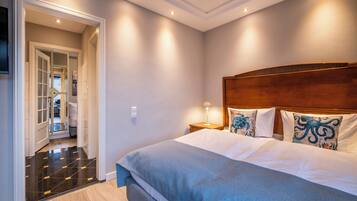 A hotel room with a large bed, a wooden headboard, and a hallway leading to a bathroom.