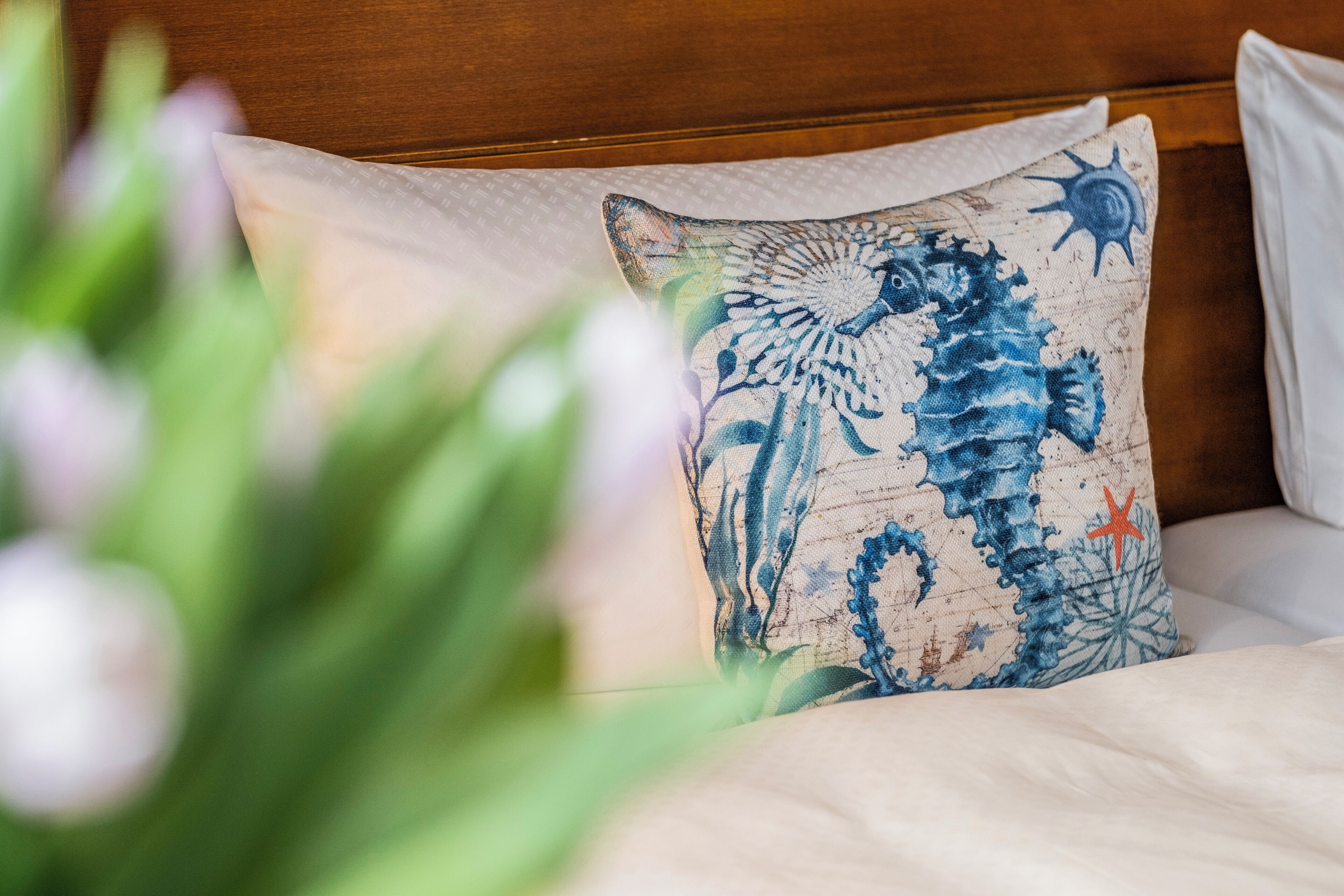 Una cama con un almohadón decorado con un diseño de caballito de mar.