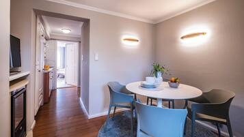 A dining area with a round table, blue chairs, and a small plant.
