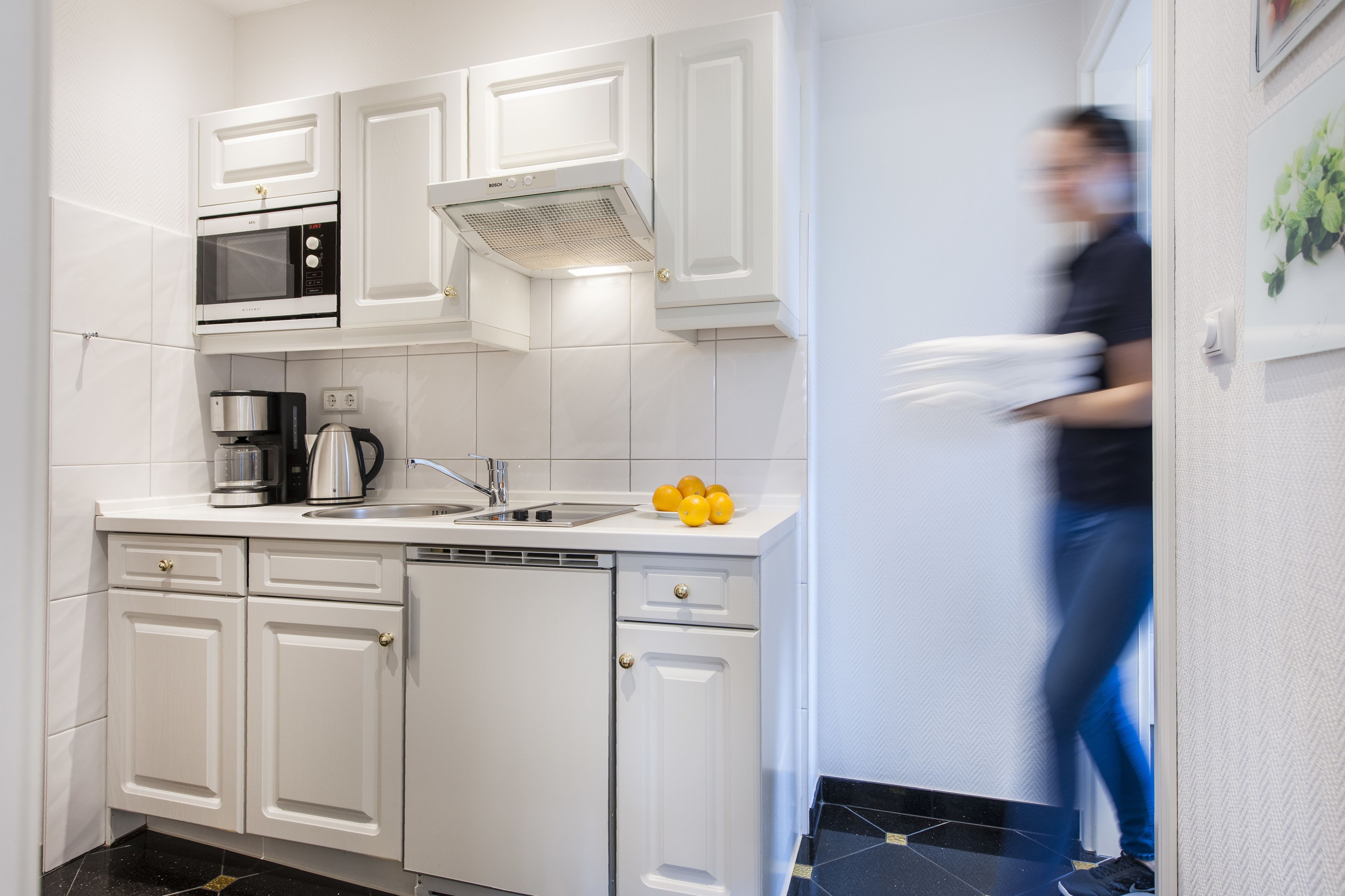A modern kitchen with white cabinetry, a built-in microwave, and a coffee maker.