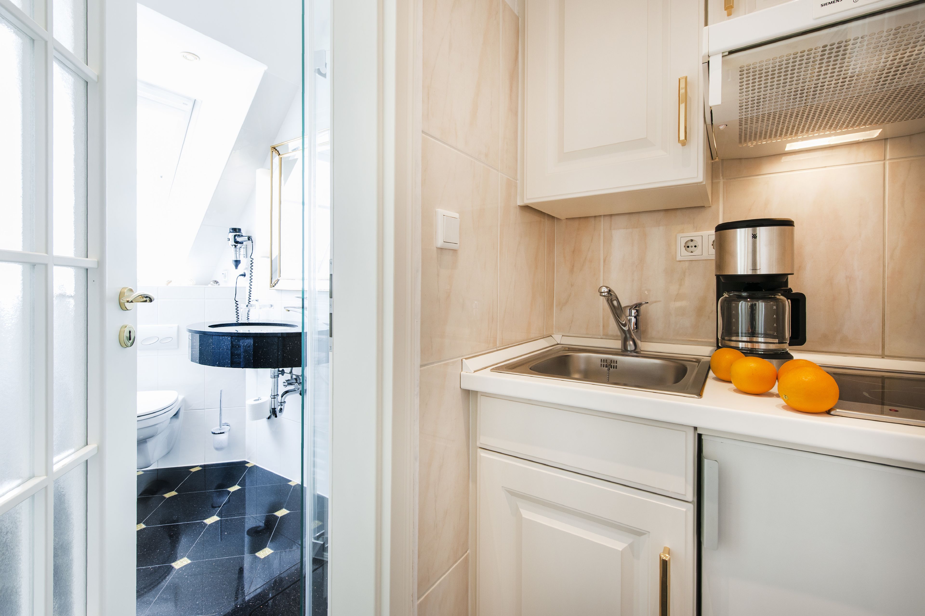Una cucina moderna con forno integrato, macchina del caffè e lavello.