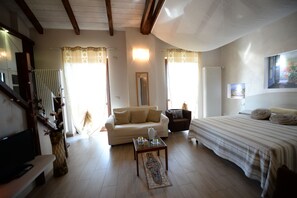 A spacious living room with a sofa, a coffee table, a TV, and a bed. - La Valle B&B (Asti)