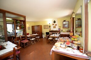 A dining area with wooden furniture, a buffet table with various food items, and a kitchen in the background. - La Valle B&B (Asti)