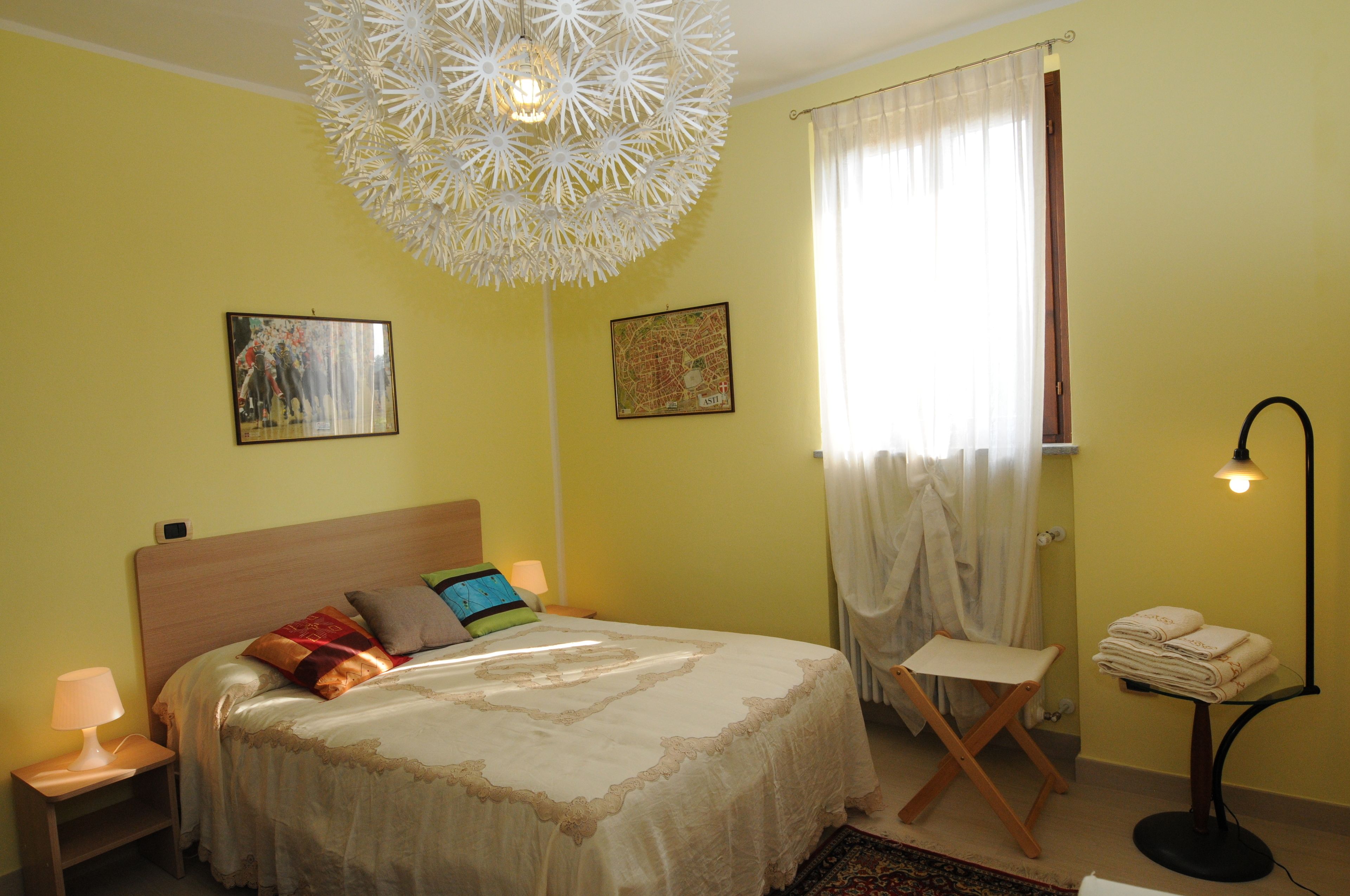 Ein Schlafzimmer mit einem Bett, einem Nachttisch, einem Stuhl, einer Lampe und einer Karte an der Wand.