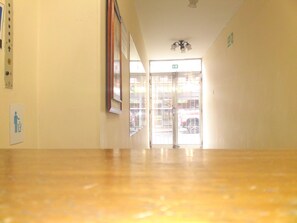 Un pasillo con piso de madera, una puerta con panel de vidrio y una lámpara en el techo.