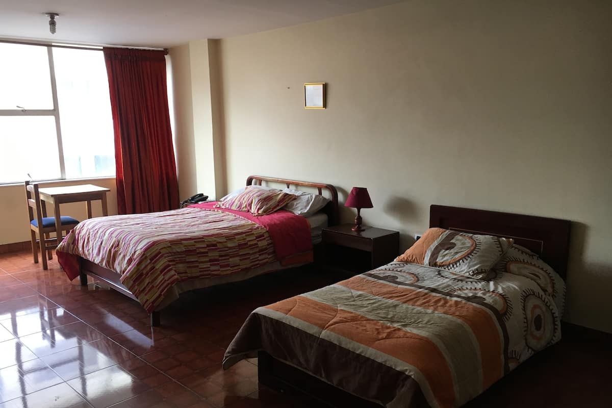 A hotel room with two beds, a desk, and a chair.