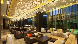 A spacious lobby with modern furniture, a bar area, and large windows offering a view of the outdoors. - Hilton Shenzhen Futian (Shenzhen)
