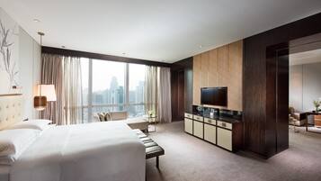 Une chambre d’hôtel moderne dotée d’un grand lit, d’une télévision à écran plat, d’un coin salon et offrant une vue sur le paysage urbain.