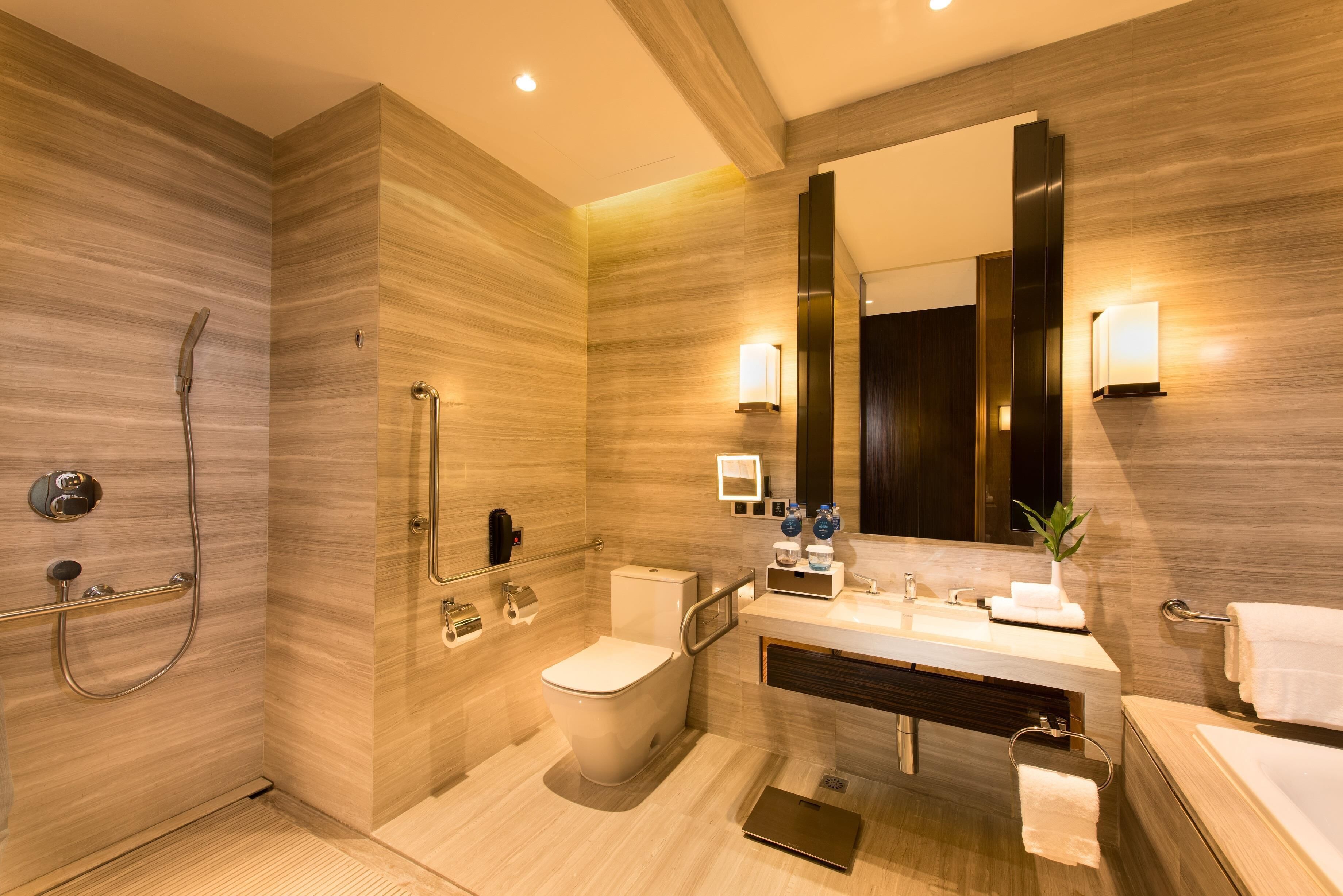 A modern bathroom with a shower, toilet, sink, and large mirror.