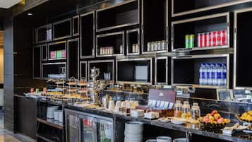 A buffet area with multiple food stations, beverage dispensers, and a refrigerator.