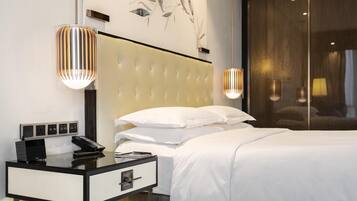 A modern hotel room with a tufted headboard, a bedside table with a phone and a lamp, and a large window with a view.