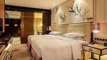 A hotel room with a large bed, bedside table, TV, and a bathroom visible through an open door.