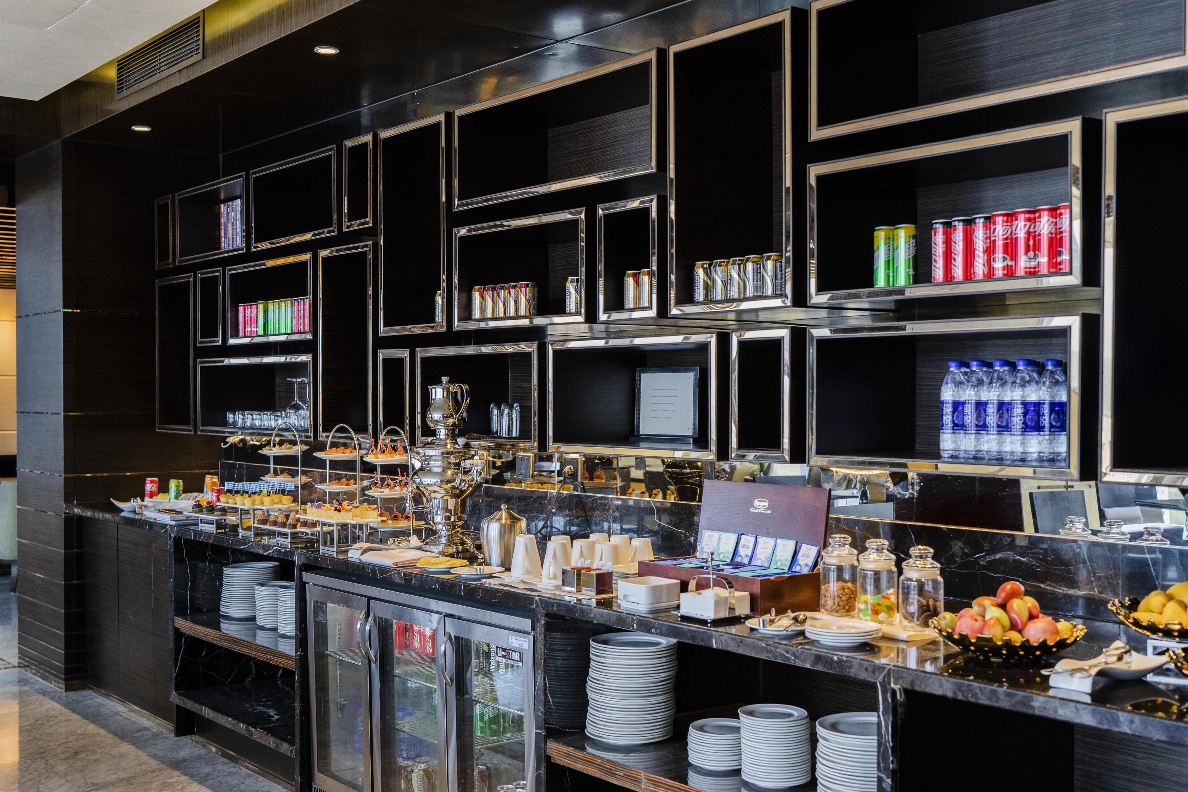 A buffet area with multiple shelves, a refrigerator, and various food items.