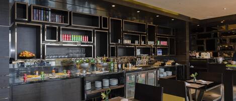 Uma área de bar moderna com prateleiras de garrafas, um balcão com copos e assentos.