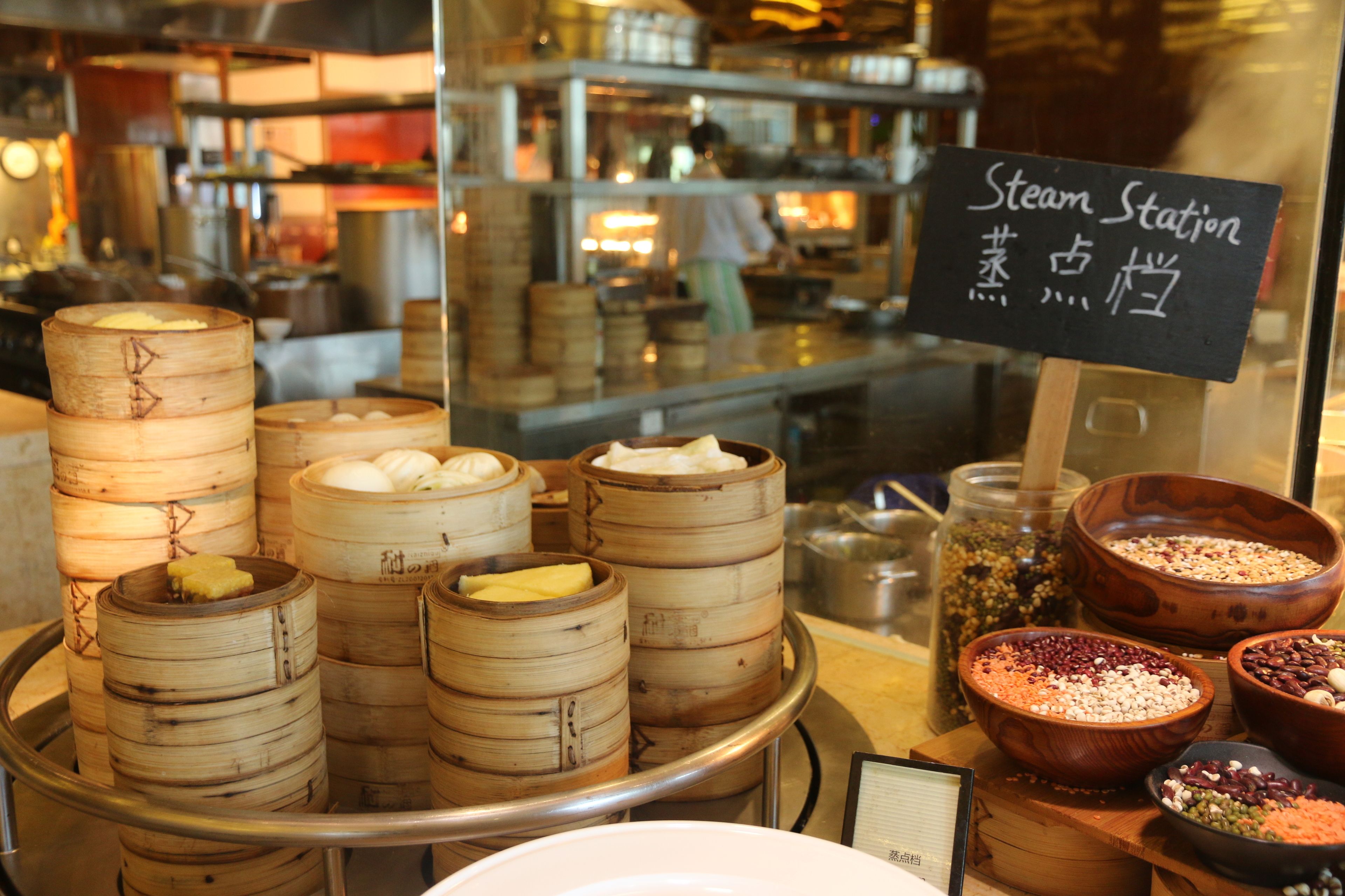 A display of steamed buns and various ingredients at a food station.
