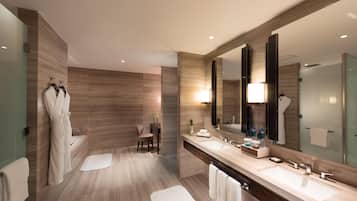 A modern bathroom with two sinks, a large mirror, and a seating area.