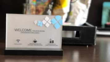 Placa de boas-vindas com lista de comodidades: Wi-Fi premium, variedade de bebidas quentes premium e lanches e bebidas geladas repostos diariamente.