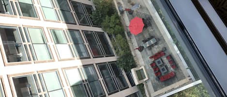 Un edificio moderno con varios pisos, amplios ventanales y un patio con mobiliario exterior.