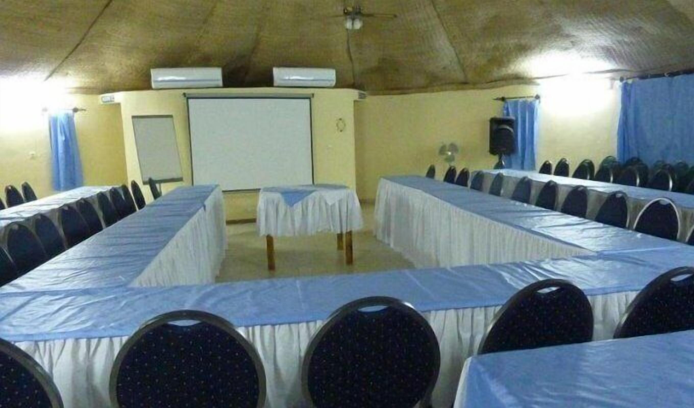 A conference room with long tables covered with white tablecloths, arranged in rows.