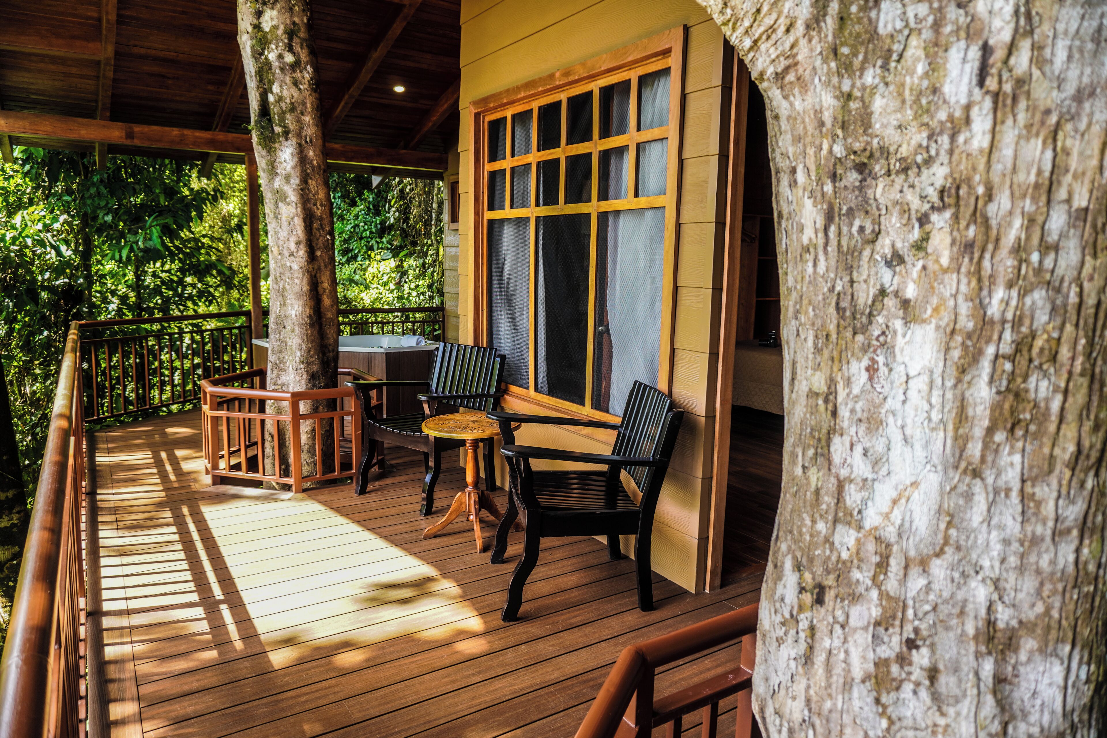 A wooden deck with a table and chairs, surrounded by trees.