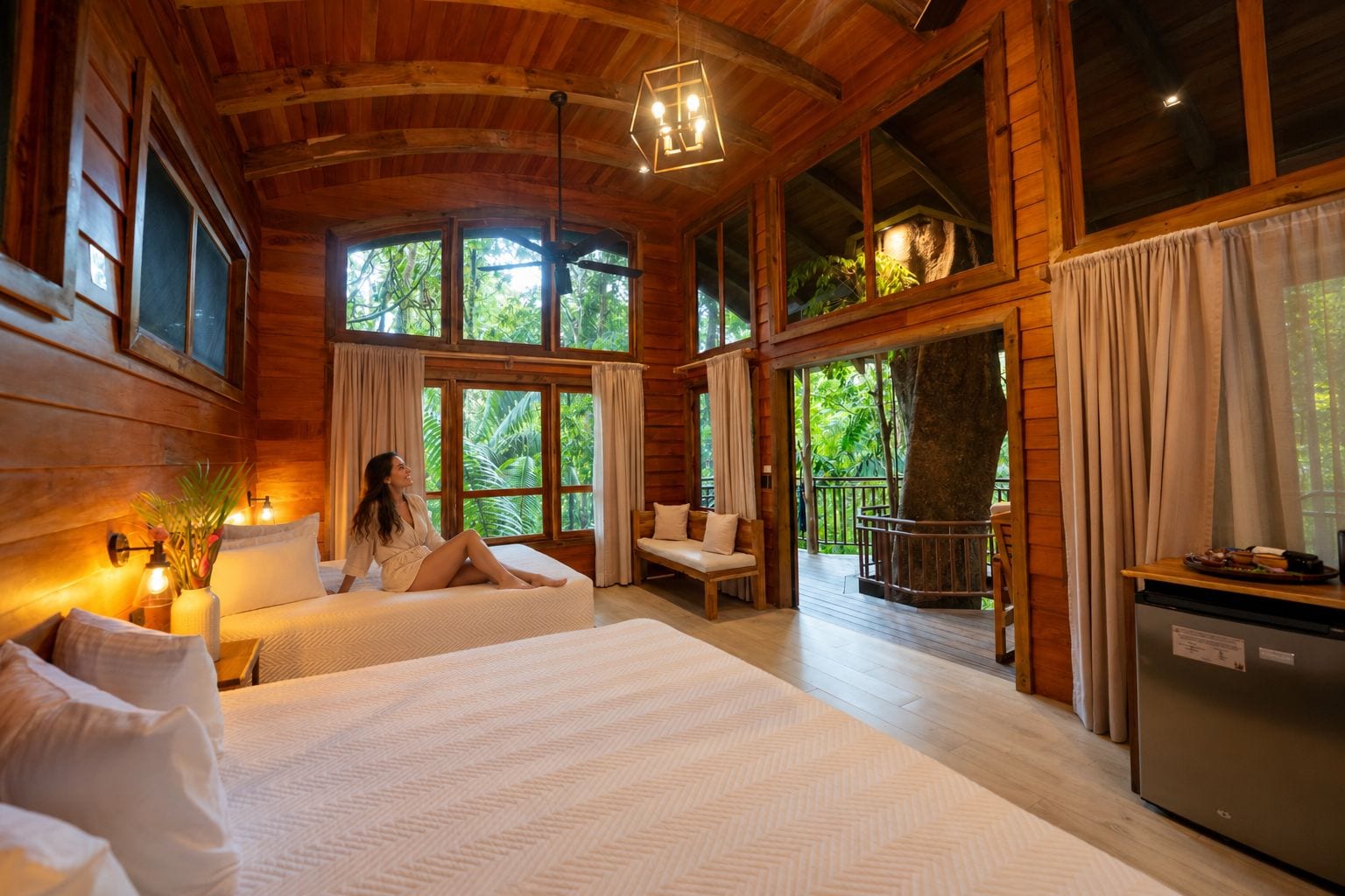 A wooden cabin with a large bed, a sitting area, and a dining space.