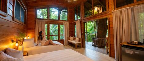 Een houten chalet met een groot bed, een zithoek en een eethoek.
