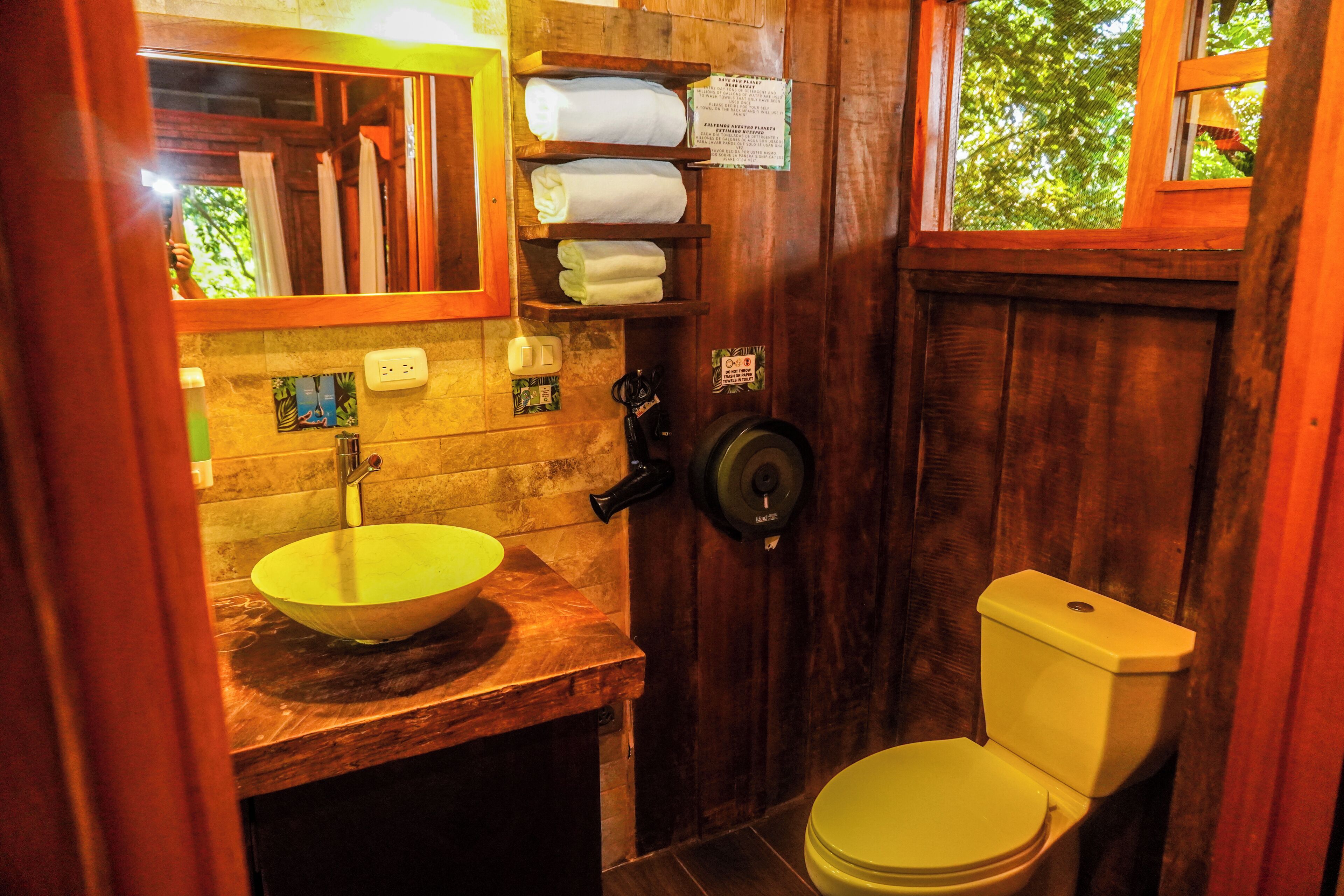 A wooden bathroom with a sink, toilet, and towel rack.