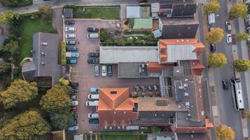 An aerial view of a residential area with multiple houses, a parking lot, and a few vehicles.
