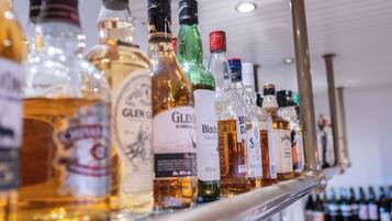 A variety of liquor bottles on a shelf in a bar setting.