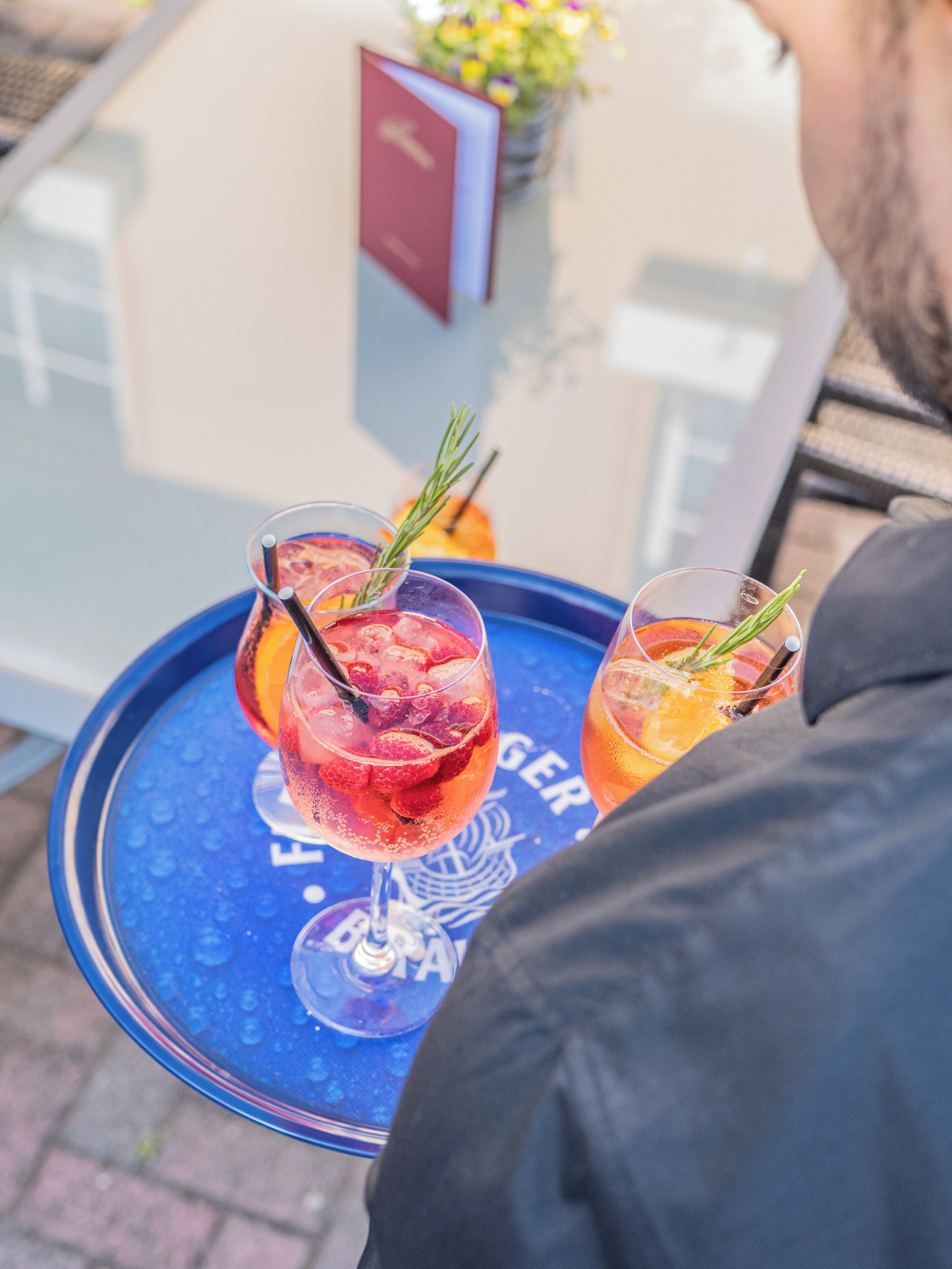 Two drinks on a blue tray with a glass of water and a menu in the background.
