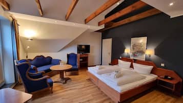 Una habitación de hotel moderna con una cama grande, un sofá, un televisor y una mesita.