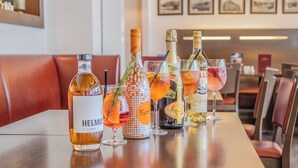 Una zona de bar con varias botellas y vasos de bebidas, incluyendo las marcas Helmut y Chandon, sobre una mesa de madera.