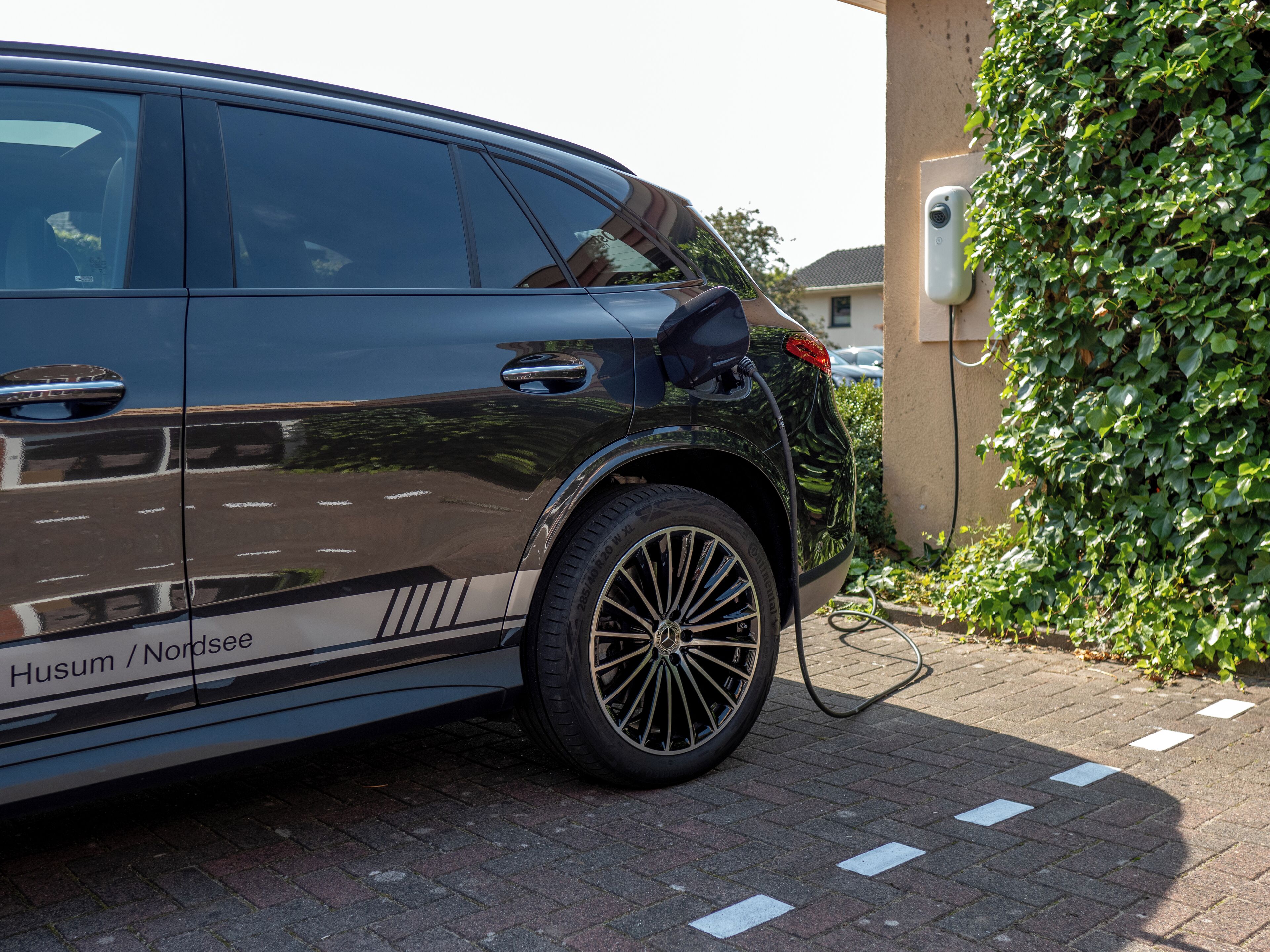 A black SUV parked on a paved area with a charging station attached to its rear.