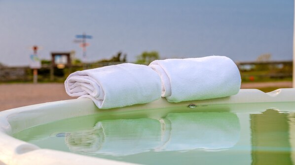 Een hottub met twee opgerolde witte handdoeken op de rand.