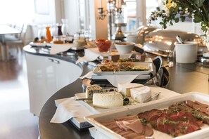 Een buffet met diverse kazen, vleessoorten en garneringen.