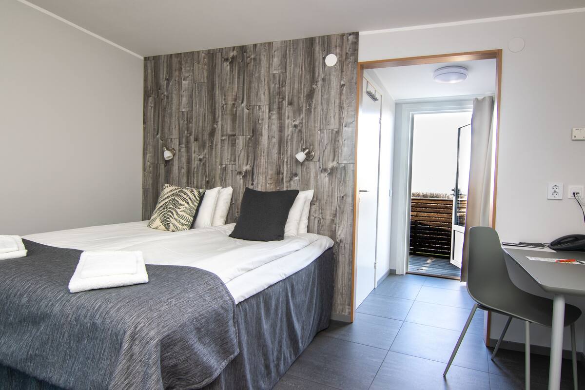 Ein Hotelzimmer mit Bett, Schreibtisch und Blick auf einen Balkon.