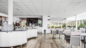 Un restaurant moderne doté d’un bar central, de meubles blancs et d’un plancher en bois.