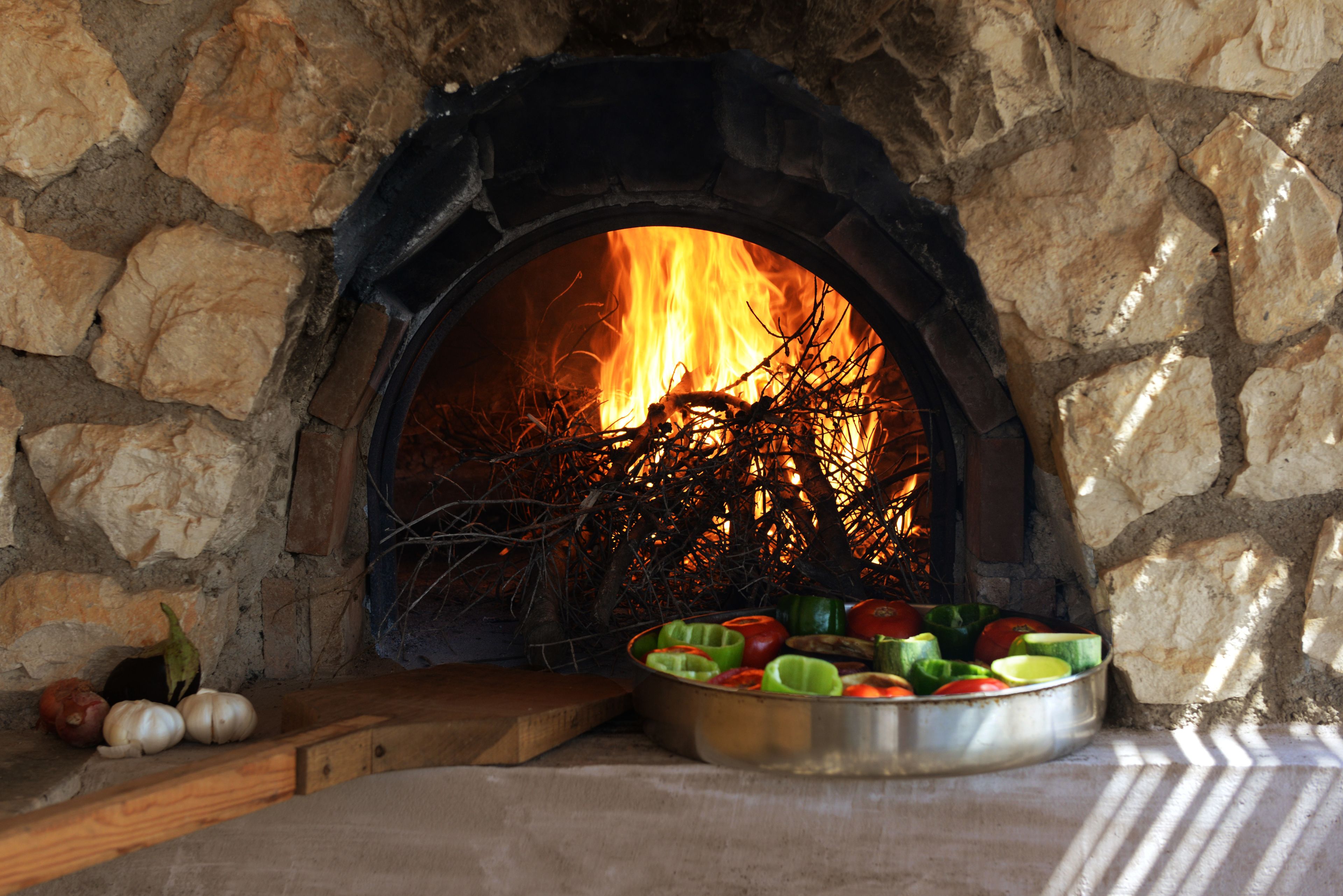 A stone fireplace with a fire burning inside, surrounded by a stone wall.