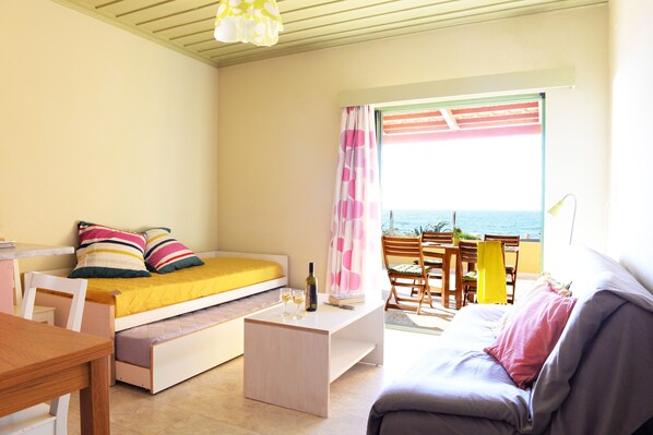 A bedroom with a bed, a sofa, a dining table, and a view of the sea. - Esperides (Trifylia)