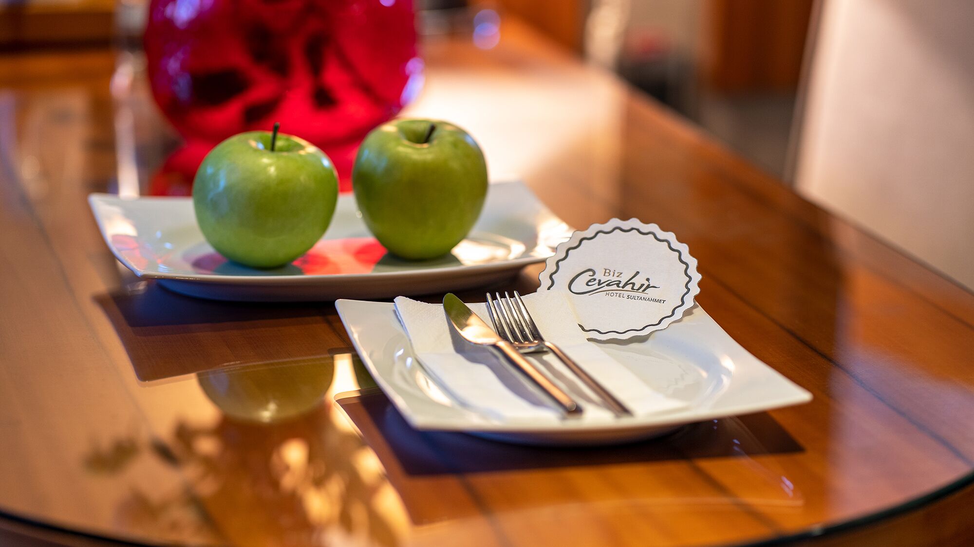 Une table avec une assiette de pommes vertes, une fourchette, un couteau et une serviette portant l’étiquette d’un hôtel.