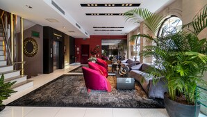 Un vestíbulo espacioso con una imponente escalera, un mostrador de recepción y una zona de estar con sillones coloridos.