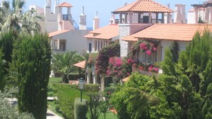 Un hôtel en bord de mer, avec des toits en tuiles de terre cuite, une végétation luxuriante et une vue dégagée sur la mer.